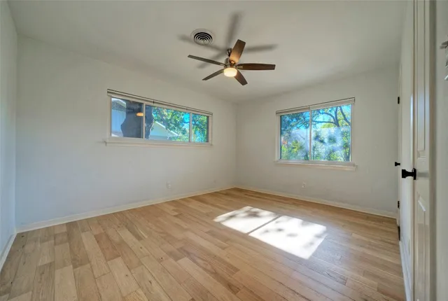 a view of empty room with wooden floor and window
