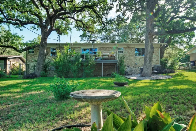 a view of a backyard with table and chairs potted plants and large tree