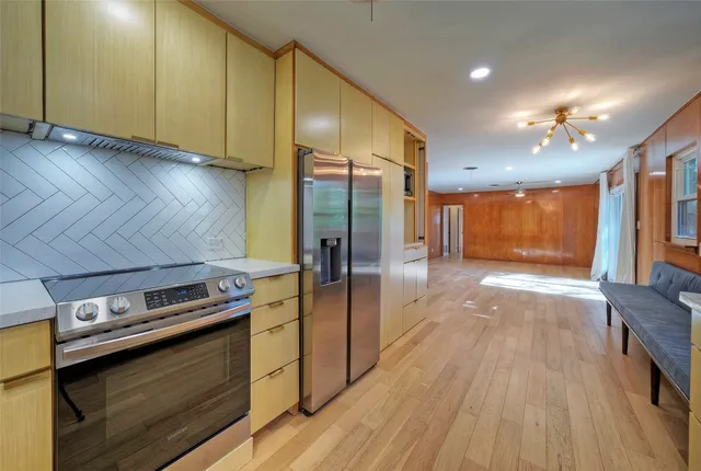 a kitchen with stainless steel appliances a stove a refrigerator and wooden floor