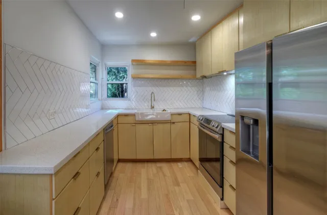 a kitchen with a sink cabinets stainless steel appliances and a window