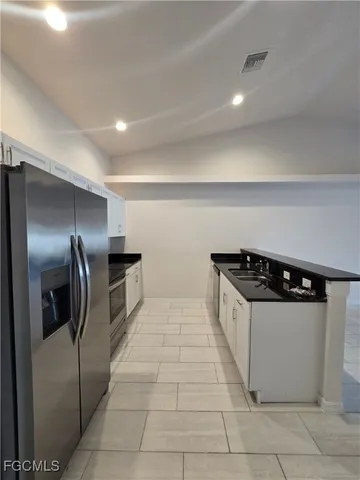 a large white kitchen with a sink and refrigerator