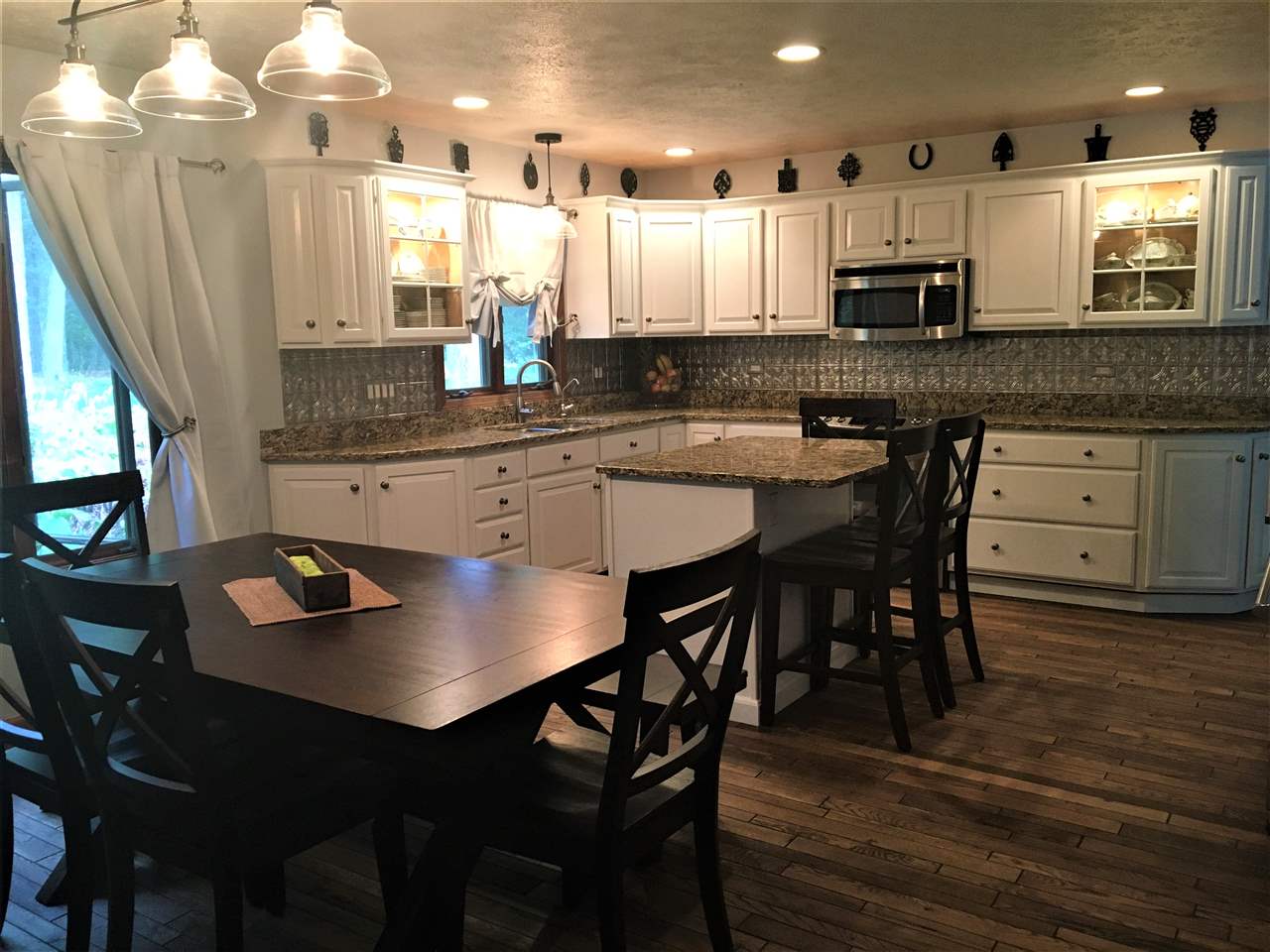 810 East Old Wagon Road Byron, IL 61010 - Photo 3 of 25 a kitchen with stainless steel appliances granite countertop a stove a sink a dining table and chairs with wooden floor