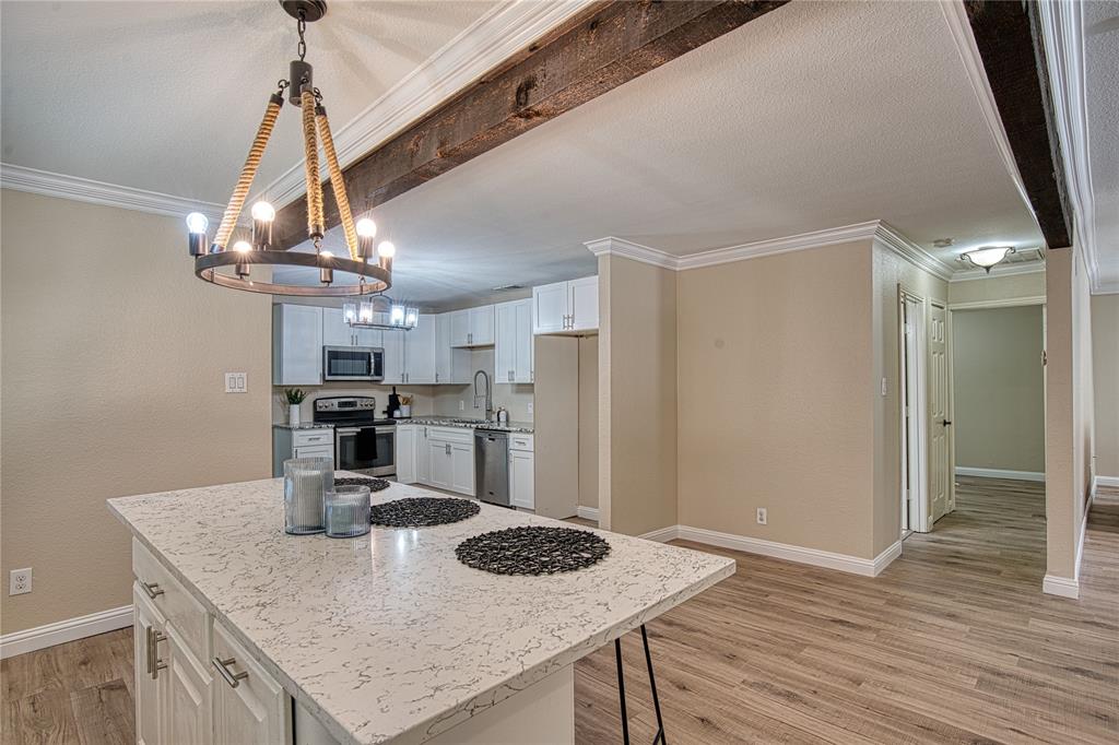 420 North Road Kennedale, TX 76060 - Photo 13 of 36 Kitchen featuring white cabinets, crown molding, light wood-type flooring, a breakfast bar, and appliances with stainless steel finishes