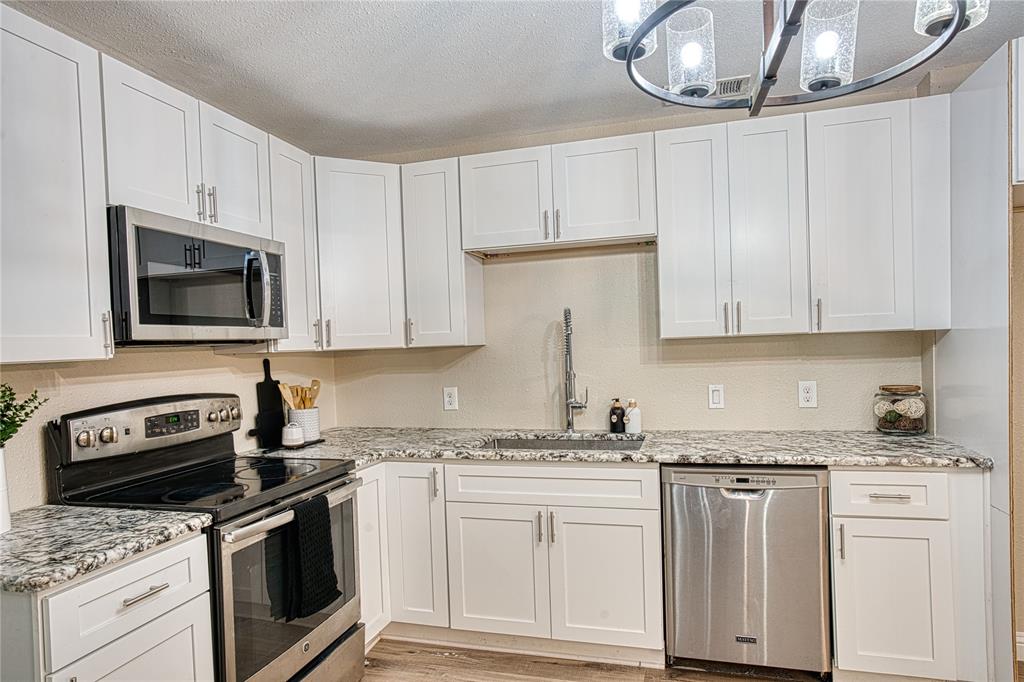 420 North Road Kennedale, TX 76060 - Photo 16 of 36 Kitchen with appliances with stainless steel finishes, white cabinetry, pendant lighting, light stone countertops, and a textured ceiling