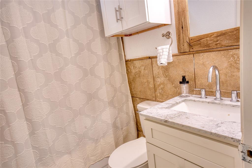 420 North Road Kennedale, TX 76060 - Photo 32 of 36 Full bath featuring a shower with shower curtain, tile walls, vanity, and wainscoting