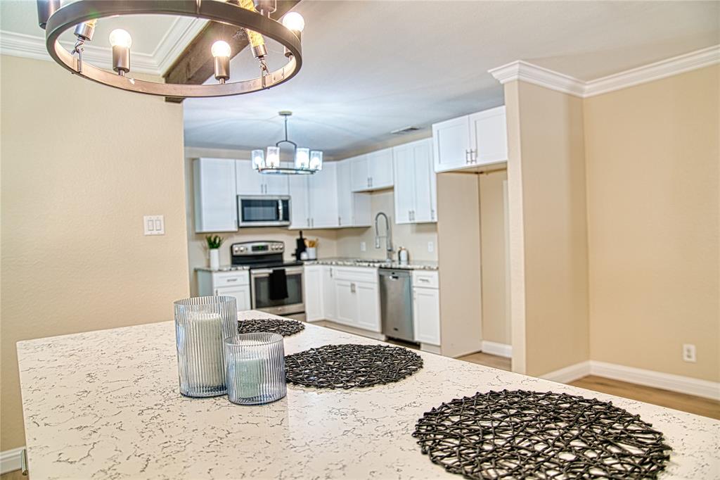 420 North Road Kennedale, TX 76060 - Photo 10 of 36 Kitchen featuring appliances with stainless steel finishes, a chandelier, light stone counters, crown molding, and white cabinets