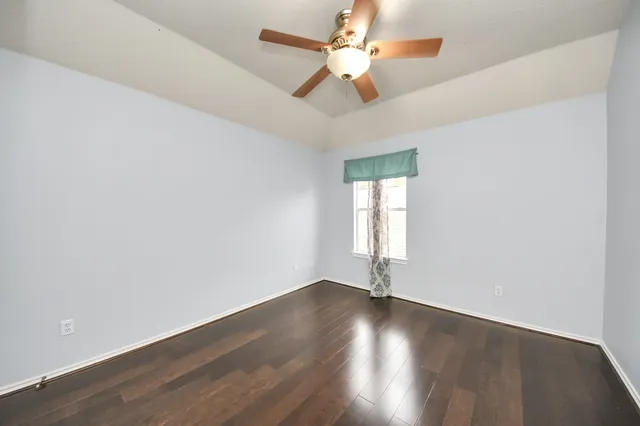 an empty room with wooden floor fan and windows
