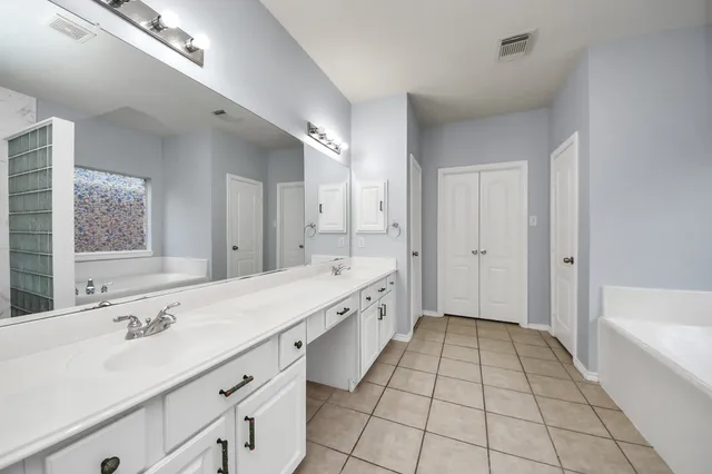 a spacious bathroom with a double vanity sink a mirror and a bathtub
