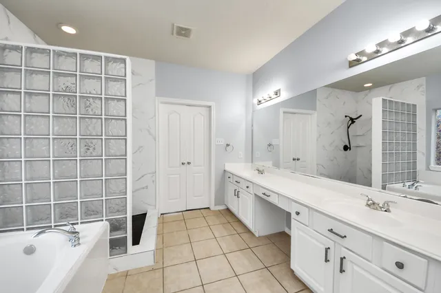 a spacious bathroom with a double vanity sink mirror and a bathtub
