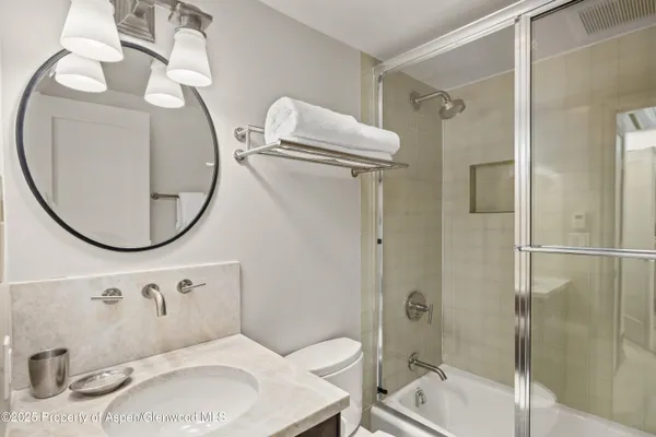 a bathroom with a sink and mirror with bathtub