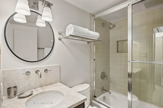 a bathroom with a sink and mirror with bathtub