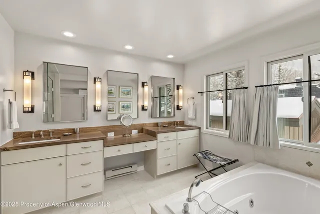 a spacious bathroom with double vanity a mirror a bathtub and a shower