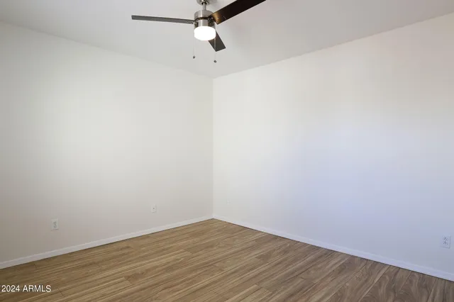 an empty room with wooden floor and fan