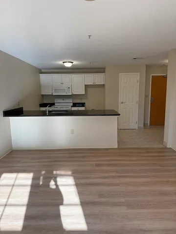 a view of a kitchen with kitchen island wooden floor and stainless steel appliances