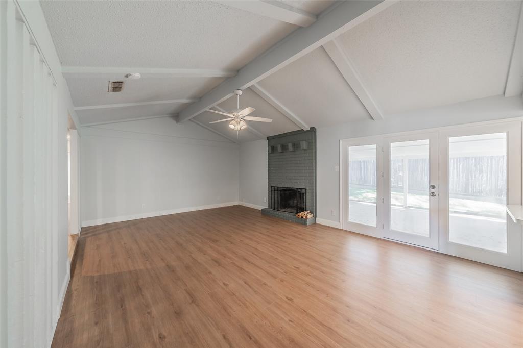 1301 Cedar Ridge Terrace Euless, TX 76039 - Photo 12 of 31 Large family room with vaulted ceiling and exposed beams, luxury vinyl floors and brick fireplace for cozy evenings.