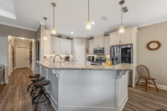 a kitchen with stainless steel appliances granite countertop a sink a stove a refrigerator and island with wooden floor