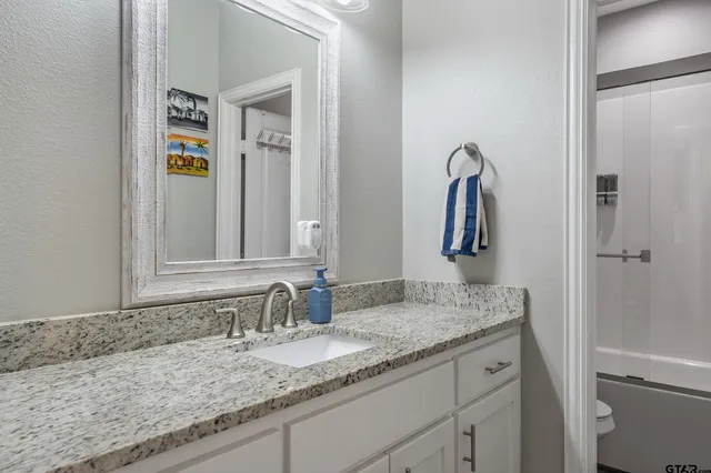a bathroom with a granite countertop double vanity sink and a mirror