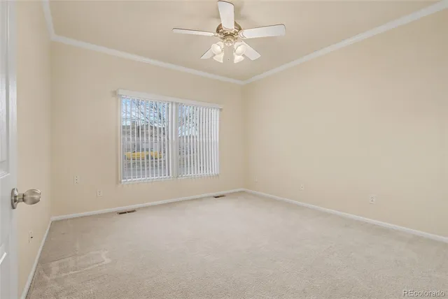 an empty room with a chandelier fan and windows