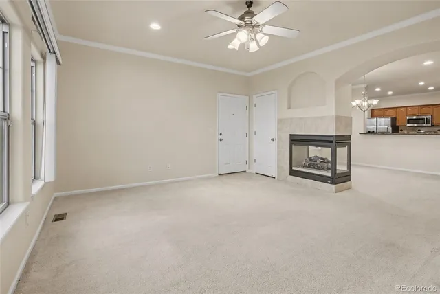 a view of an empty room with a chandelier fan