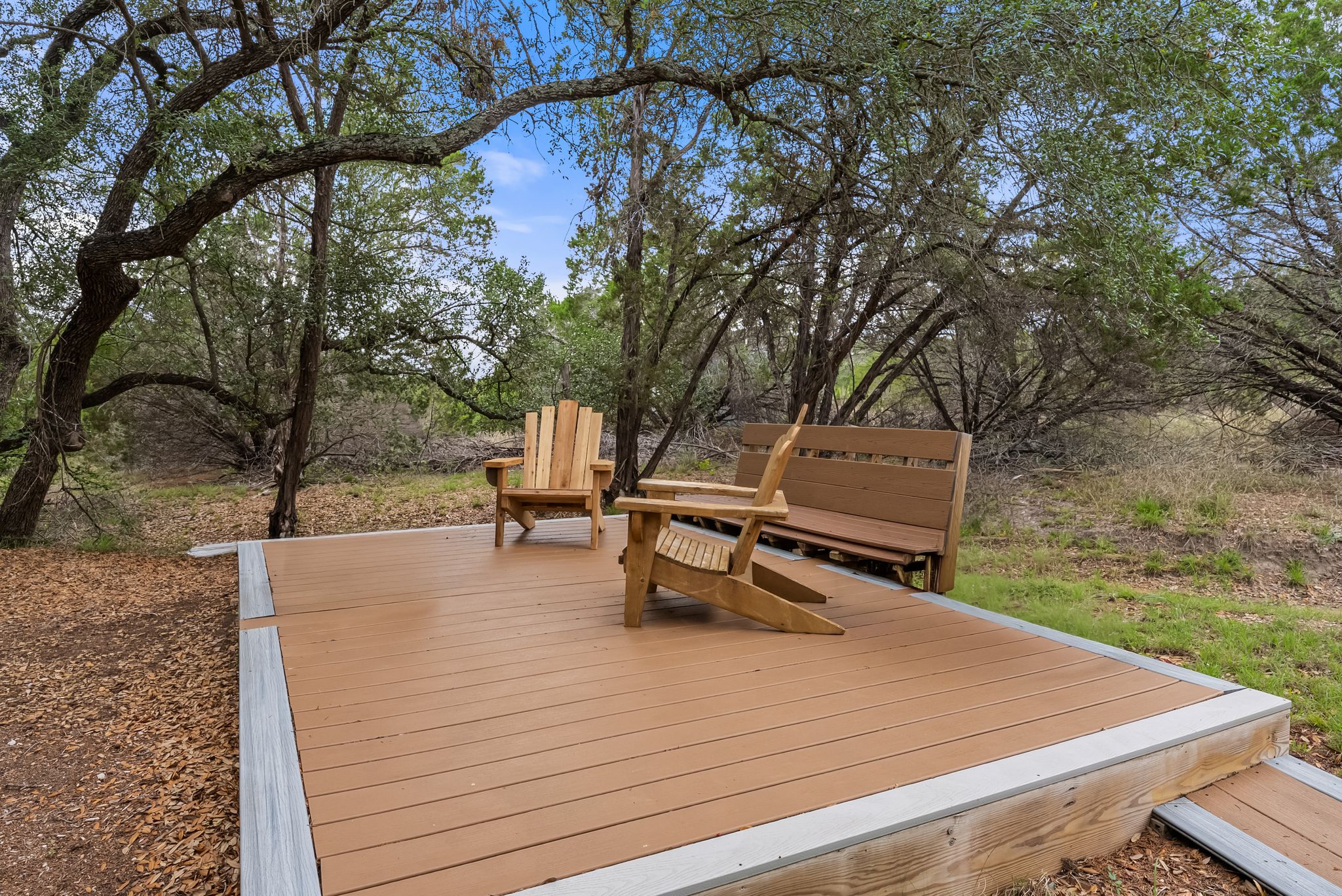 200 Vista West Ranch Road Dripping Springs, TX 78620 - Photo 17 of 20 Outdoor deck with composite decking and light gray trim, surrounded by mature trees