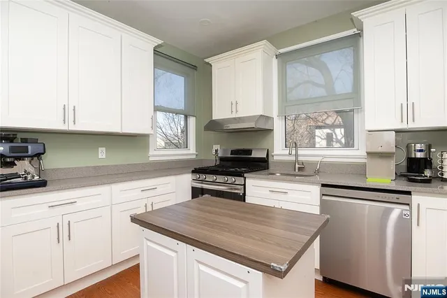 a kitchen with granite countertop a sink stainless steel appliances and cabinets