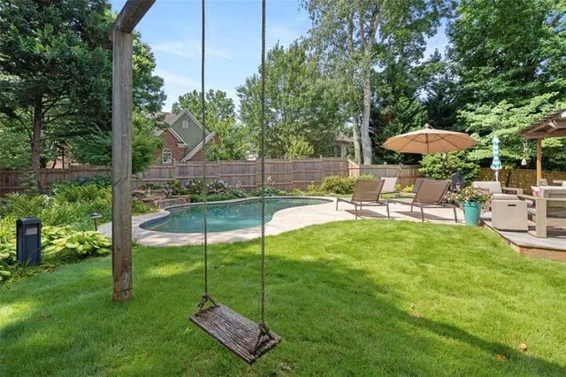 a view of a backyard with table and chairs potted plants and large tree