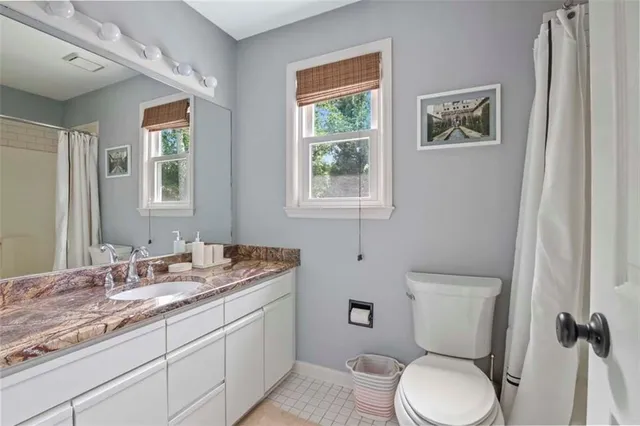 a bathroom with a granite countertop toilet sink and mirror