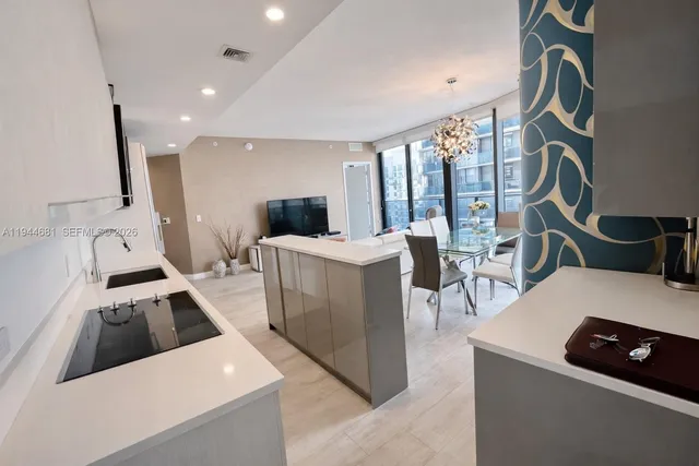 a kitchen that has a lot of white cabinets and couches with wooden floor
