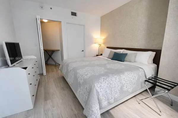 a bedroom with a bed and a flat tv screen on the dresser