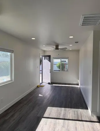 an empty room with wooden floor and windows