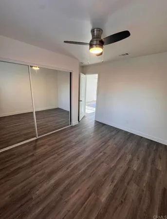 an empty room with wooden floor and a ceiling fan