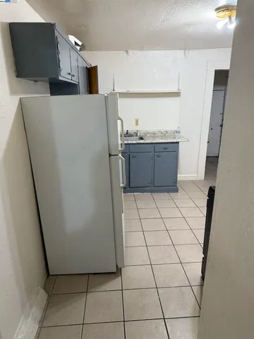 a view of a refrigerator in kitchen and an empty room