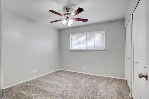 an empty room with a chandelier fan and windows
