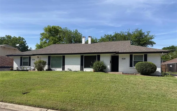 a front view of a house with a yard and trees
