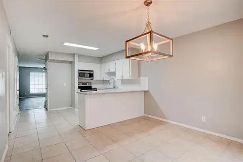 a kitchen with white cabinets and window