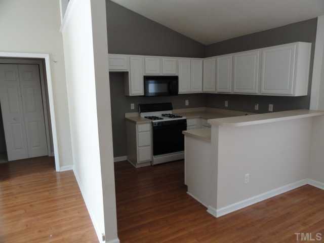 3924 Mardela Spring Drive Raleigh, NC 27616 - Photo 3 of 5 a kitchen with cabinets stainless steel appliances and wooden floor
