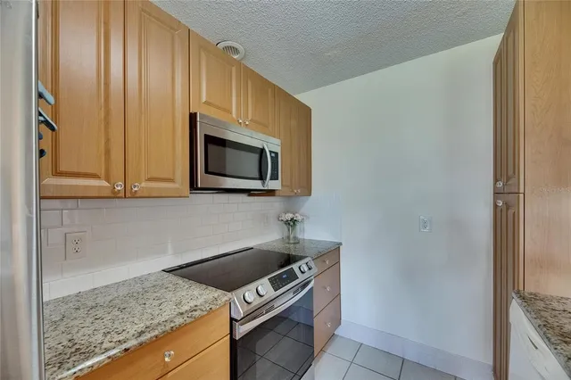 a kitchen with granite countertop cabinets stainless steel appliances and a counter space