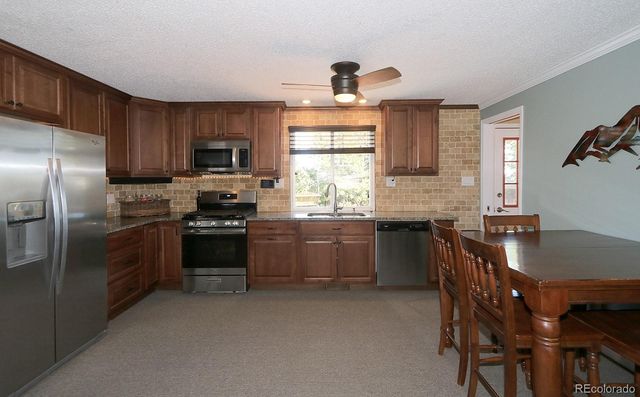 a kitchen with granite countertop a refrigerator stove top oven and sink