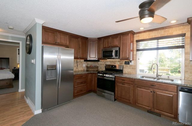 a kitchen with stainless steel appliances granite countertop a refrigerator a sink dishwasher a stove and a microwave oven with cabinets