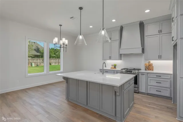 a kitchen with kitchen island granite countertop a sink a counter space appliances and cabinets