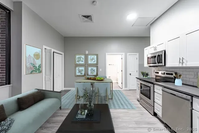 a living room with stainless steel appliances furniture and a kitchen view