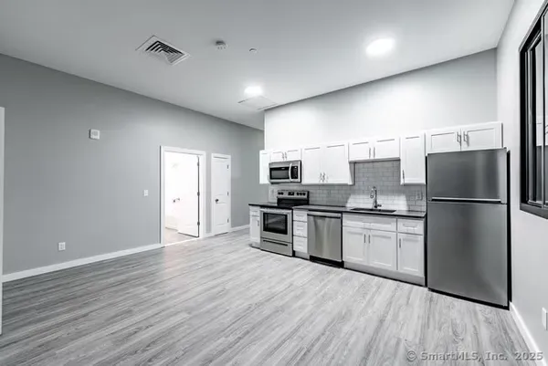 a kitchen with stainless steel appliances granite countertop a refrigerator a sink dishwasher a stove and a refrigerator with wooden floor