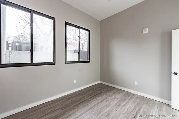 an empty room with wooden floor and windows