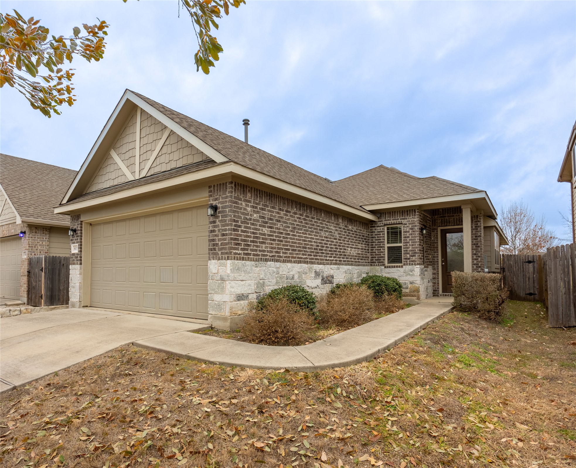 Ranch-style house featuring driveway, a shingled roof, an attached garage, and brick siding