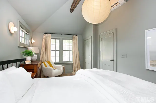 a bedroom with a large bed and windows