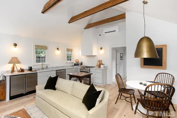 a living room with stainless steel appliances kitchen island granite countertop a table chairs a sink dishwasher and cabinets