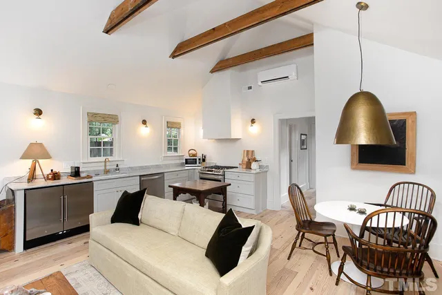 a living room with stainless steel appliances kitchen island granite countertop a table chairs a sink dishwasher and cabinets