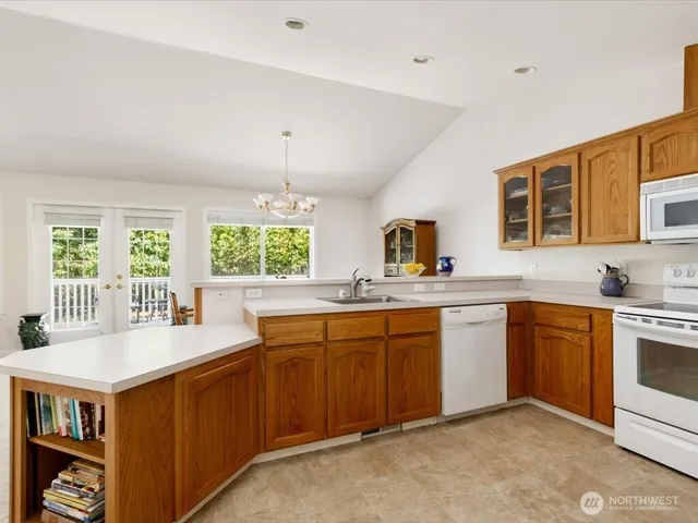 a kitchen with granite countertop a sink dishwasher stove and cabinets