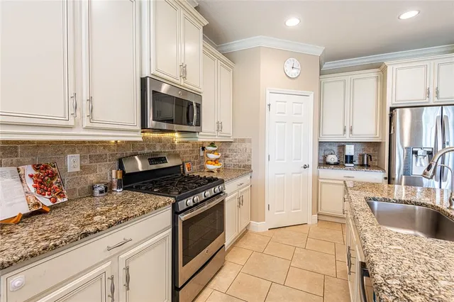 a kitchen with granite countertop a sink stove top oven and refrigerator