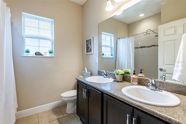 a bathroom with a granite countertop sink a toilet and a mirror